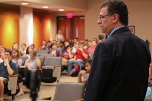 Pictured from the back, Dr. Paul Baxa addresses an audience at a conference.